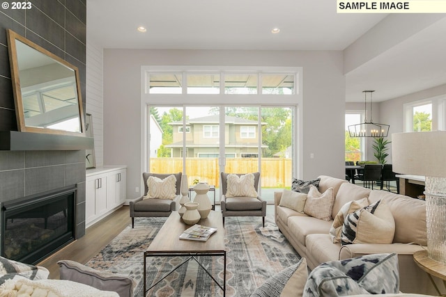 living room featuring a notable chandelier, light wood-type flooring, and a tiled fireplace