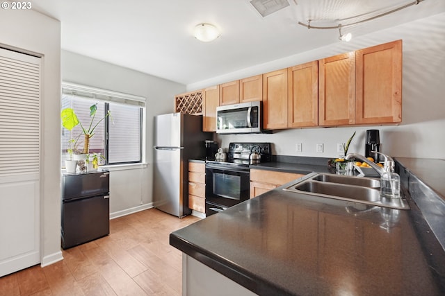 kitchen featuring track lighting, stainless steel appliances, light wood-type flooring, and sink