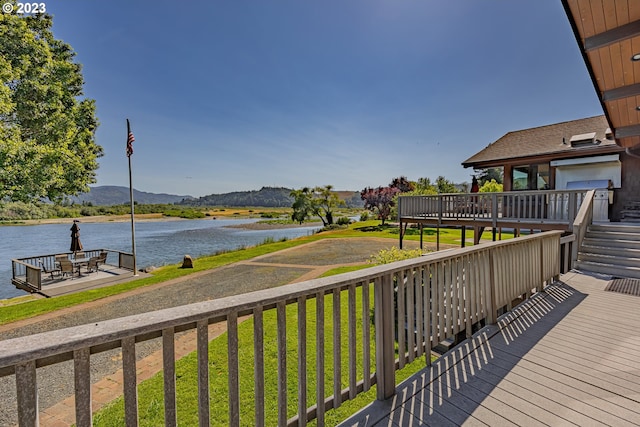 wooden terrace with a water and mountain view and a lawn