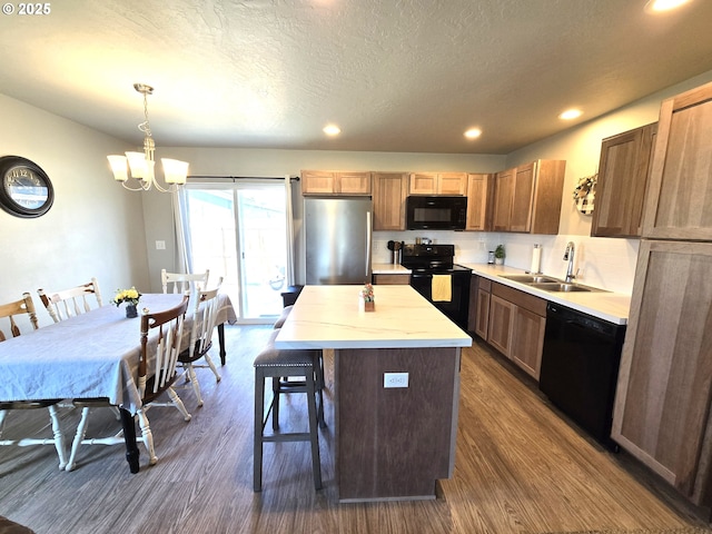 731 NE 11th St, Hermiston, OR 97838 - kitchen featuring black appliances, a sink, dark wood-type flooring, a kitchen island, and a chandelier
