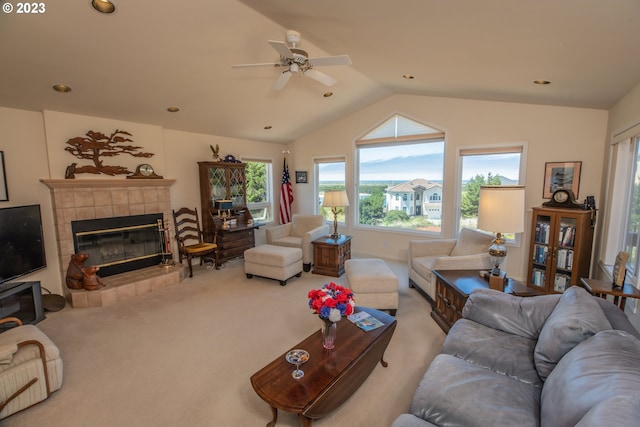 living room featuring vaulted ceiling, a fireplace, ceiling fan, and carpet