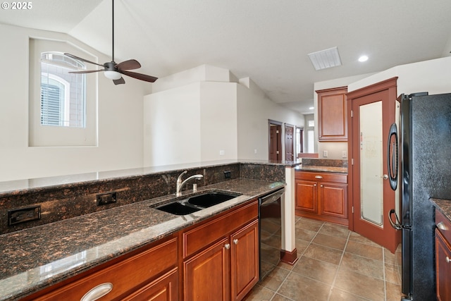 kitchen with a sink, black appliances, ceiling fan, dark stone counters, and tile patterned flooring