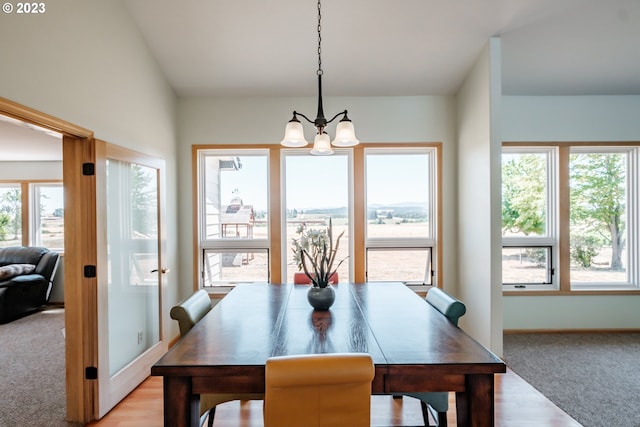 carpeted dining space featuring an inviting chandelier and a wealth of natural light