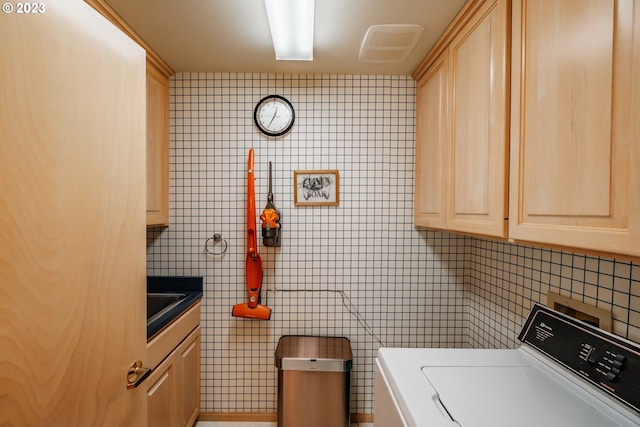 laundry area featuring cabinets, washer / dryer, and tile walls