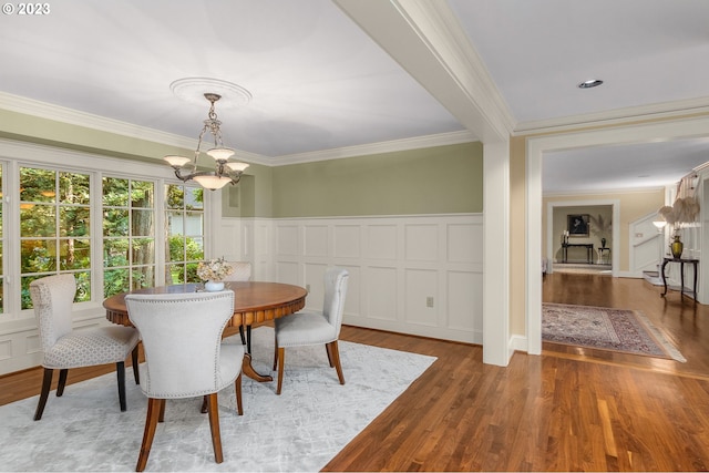 dining area featuring light hardwood / wood-style floors, ornamental molding, and a notable chandelier