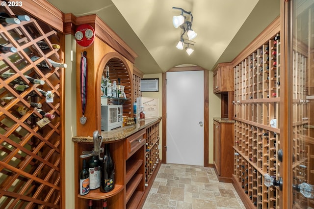 wine cellar with indoor bar, vaulted ceiling, light tile floors, and track lighting