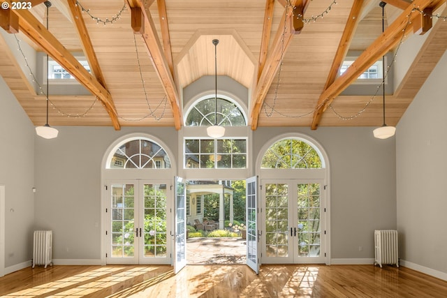 interior space featuring french doors, beam ceiling, radiator heating unit, and light hardwood / wood-style flooring