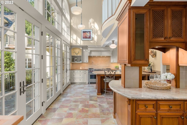 kitchen with a high ceiling, light tile floors, tasteful backsplash, and pendant lighting