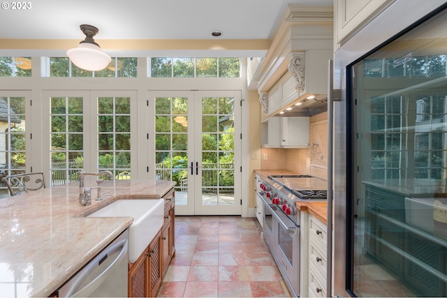 kitchen featuring backsplash, light stone countertops, appliances with stainless steel finishes, and french doors