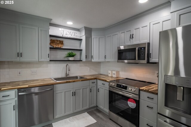kitchen with open shelves, butcher block countertops, tasteful backsplash, a sink, and appliances with stainless steel finishes