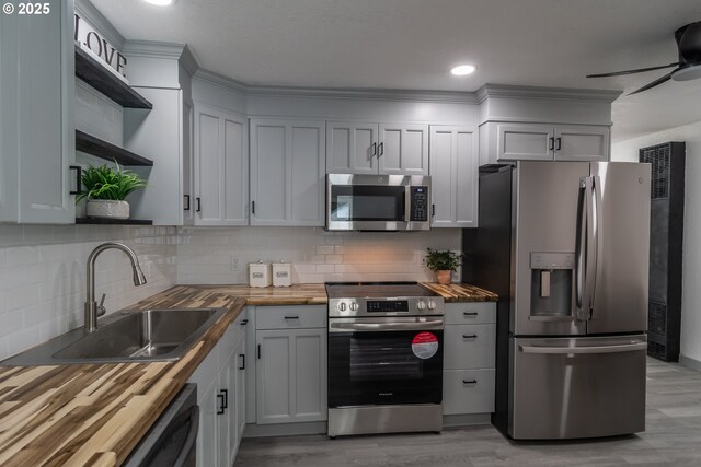 kitchen featuring tasteful backsplash, open shelves, a sink, stainless steel appliances, and butcher block countertops