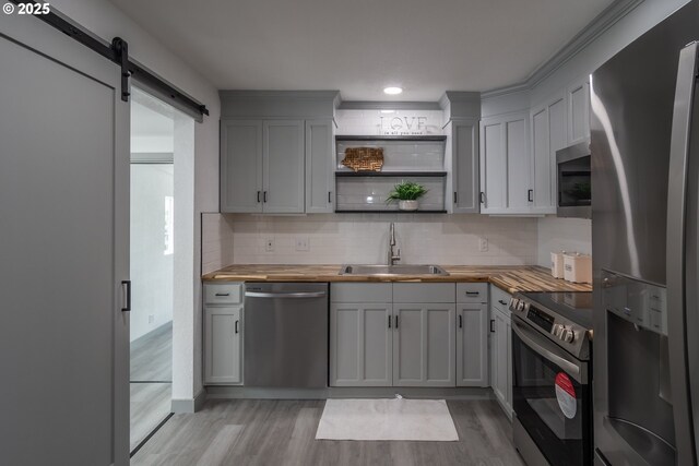 kitchen featuring butcher block countertops, a sink, light wood finished floors, and stainless steel appliances