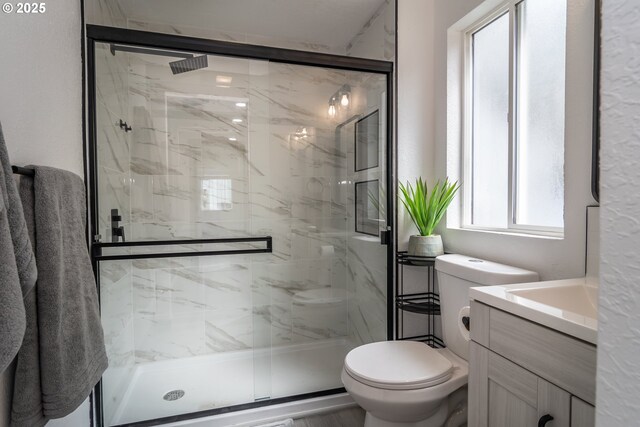 full bathroom with a marble finish shower, vanity, and toilet