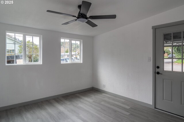 spare room with light wood-style floors, baseboards, and a ceiling fan