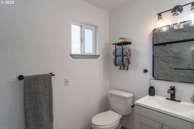bathroom with vanity, backsplash, toilet, and a shower