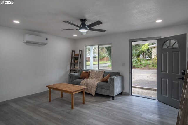 living room with baseboards, ceiling fan, light wood-type flooring, recessed lighting, and a wall unit AC