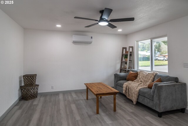 living room featuring a ceiling fan, a wall mounted AC, light wood-style flooring, and recessed lighting
