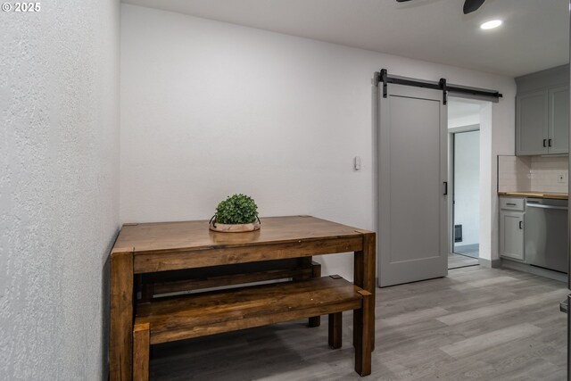 dining room with recessed lighting, ceiling fan, a barn door, and light wood-style floors