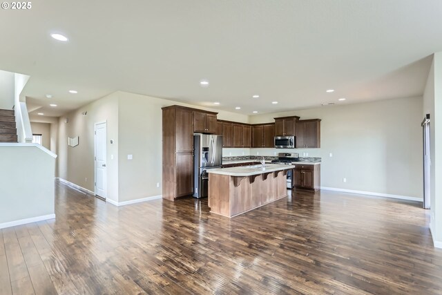 7359 NW 168th Ave, Portland, OR 97229 - kitchen with stainless steel appliances, dark wood-style flooring, light countertops, open floor plan, and a breakfast bar area
