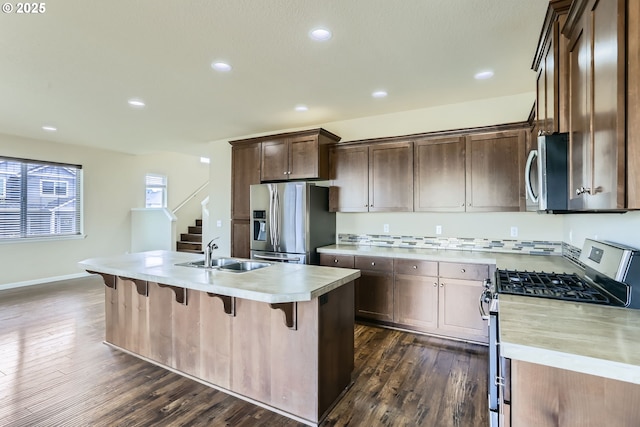 7359 NW 168th Ave, Portland, OR 97229 - kitchen featuring stainless steel appliances, light countertops, dark wood-style floors, a breakfast bar, and a kitchen island with sink