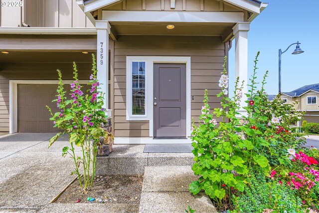 7359 NW 168th Ave, Portland, OR 97229 - entrance to property featuring board and batten siding, an attached garage, and concrete driveway