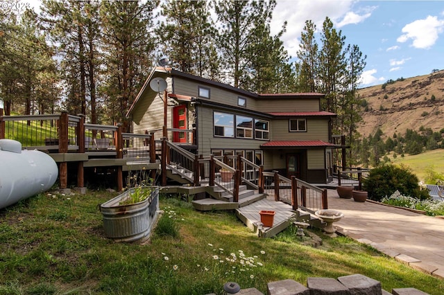 back of house with a lawn and a deck with mountain view