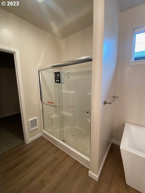 223 N Johnson St, Prairie City, OR 97869 - full bathroom featuring wood finished floors, a shower stall, and a soaking tub