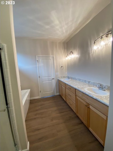 223 N Johnson St, Prairie City, OR 97869 - full bath with wood finished floors, a garden tub, double vanity, and an enclosed shower