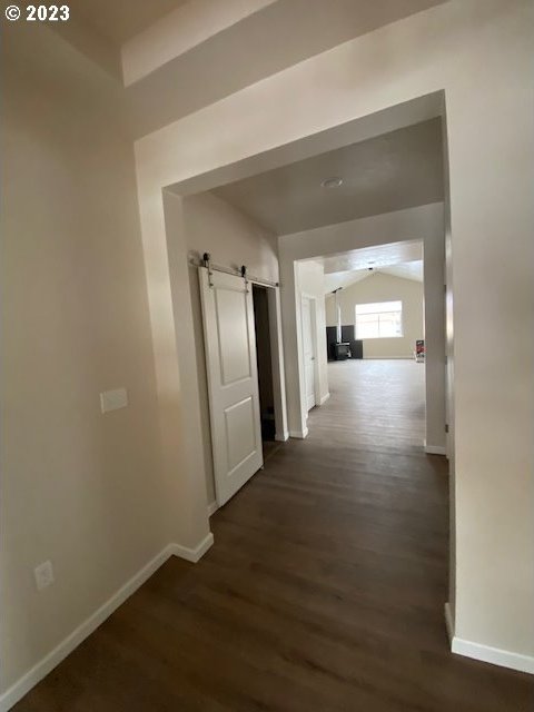 223 N Johnson St, Prairie City, OR 97869 - hallway featuring a barn door, dark wood-style flooring, and lofted ceiling
