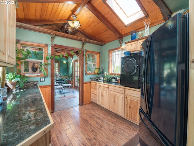 kitchen featuring wooden ceiling, washer / clothes dryer, lofted ceiling with skylight, light hardwood / wood-style flooring, and black fridge