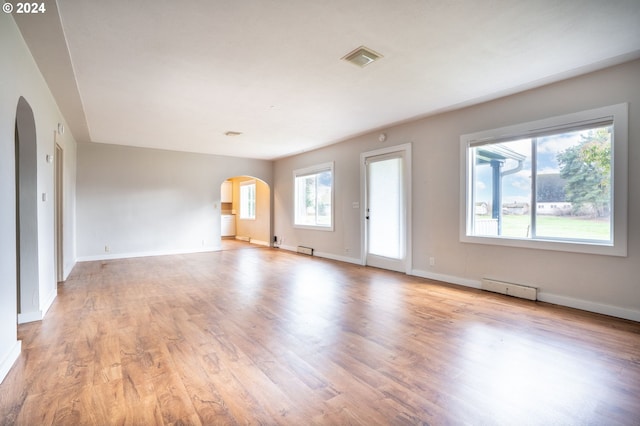 unfurnished living room featuring light wood-type flooring and a baseboard heating unit