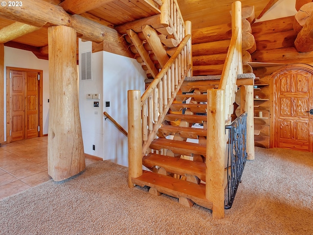 staircase featuring beam ceiling, log walls, wood ceiling, and light colored carpet