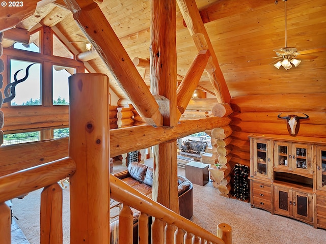 interior space featuring log walls, ceiling fan, beamed ceiling, wooden ceiling, and light carpet