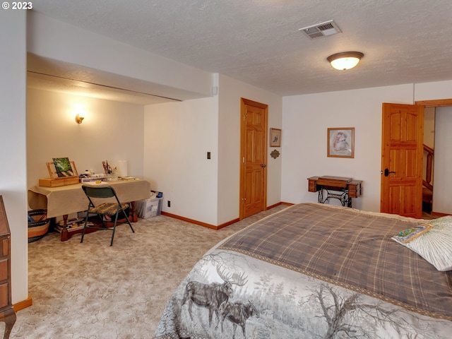 bedroom with a textured ceiling and light colored carpet