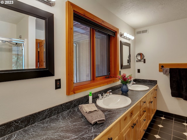 bathroom featuring double sink, a textured ceiling, tile floors, and oversized vanity