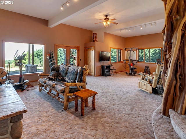 carpeted living room with french doors, track lighting, beam ceiling, and ceiling fan