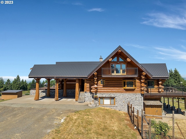 cabin featuring a balcony and a front lawn