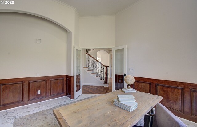 office area with arched walkways, ornamental molding, and wainscoting