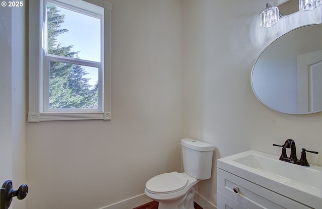 half bathroom featuring baseboards, toilet, and vanity