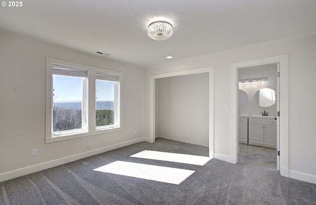 unfurnished bedroom featuring visible vents, ornamental molding, a sink, baseboards, and carpet flooring