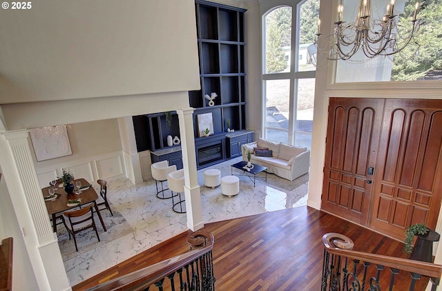 entrance foyer featuring an inviting chandelier, a glass covered fireplace, wood finished floors, and a wealth of natural light