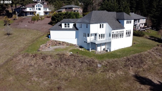 back of house featuring a yard and a shingled roof