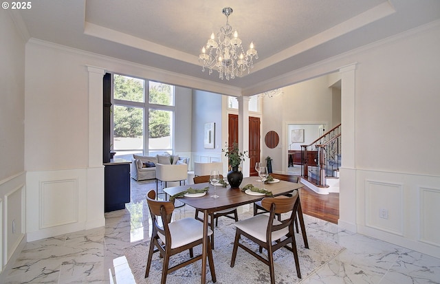 dining area with wainscoting, marble finish floor, stairs, and a decorative wall