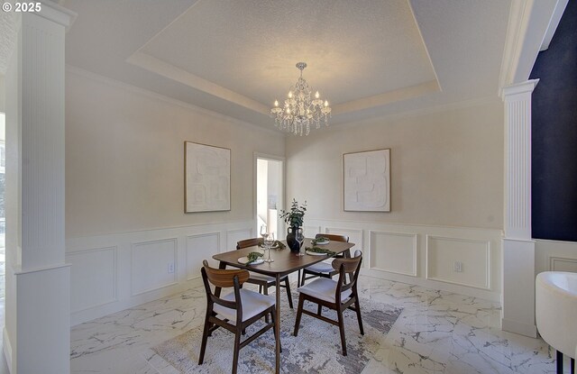 dining space with decorative columns, marble finish floor, an inviting chandelier, and a decorative wall