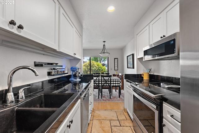 5250 S Landing Dr Unit 111B1, Portland, OR 97239 - kitchen featuring stainless steel appliances, dark countertops, white cabinetry, recessed lighting, and stone tile floors