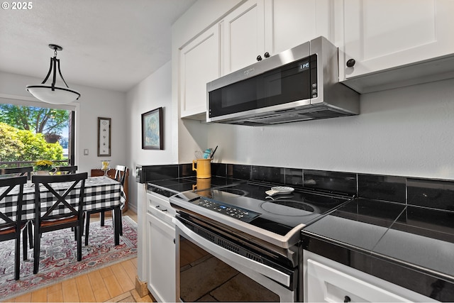 5250 S Landing Dr Unit 111B1, Portland, OR 97239 - kitchen featuring stainless steel appliances, white cabinets, light wood-style flooring, and hanging light fixtures