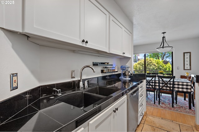 5250 S Landing Dr Unit 111B1, Portland, OR 97239 - kitchen featuring dark countertops, stainless steel dishwasher, white cabinets, and pendant lighting