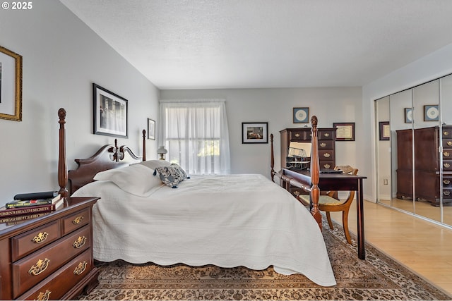 5250 S Landing Dr Unit 111B1, Portland, OR 97239 - bedroom with wood finished floors, a closet, and a textured ceiling