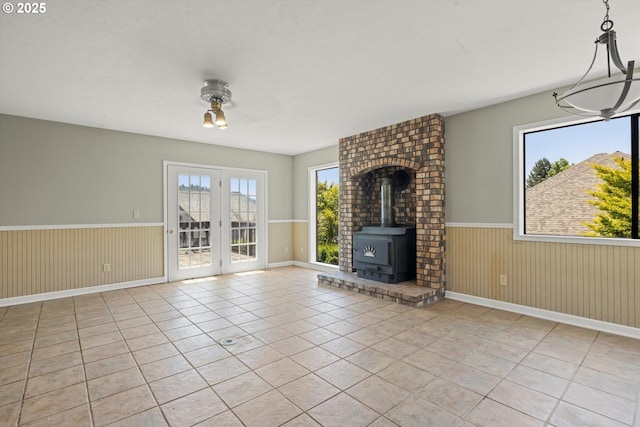 11185 SE Saint Lucy Ln, Happy Valley, OR 97086 - unfurnished living room with a wainscoted wall, a wood stove, light tile patterned floors, ceiling fan, and wooden walls
