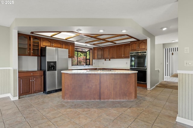 11185 SE Saint Lucy Ln, Happy Valley, OR 97086 - kitchen featuring stainless steel appliances, a center island, tile countertops, glass insert cabinets, and recessed lighting